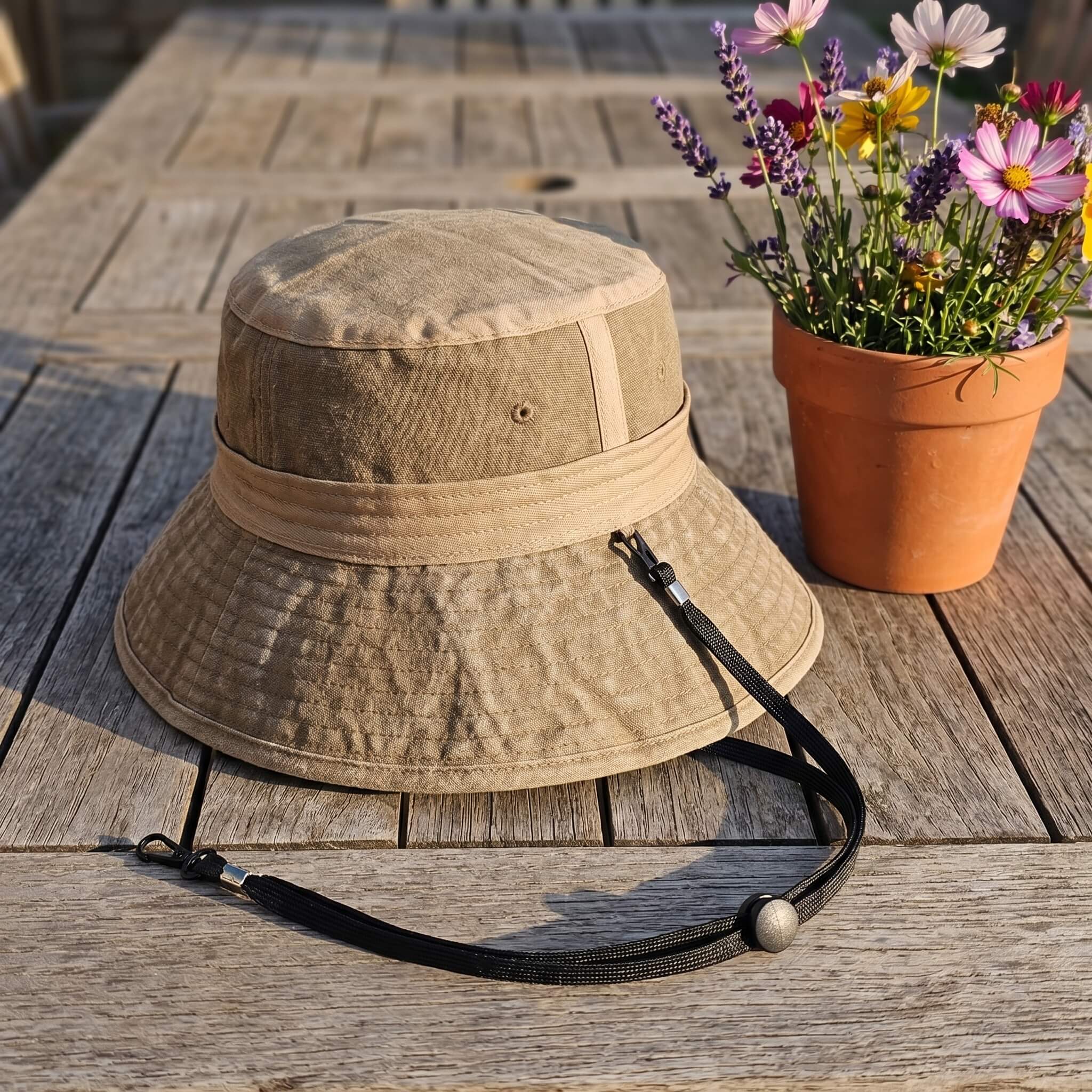 Meriple khaki cotton sun hat on a wooden table with its free detachable windproof lanyard.